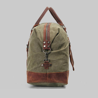 Sac de voyage en toile verte avec détails en cuir marron, fermeture éclair robuste, poignée supérieure et bandoulière ajustable. Accessoire mode pratique.