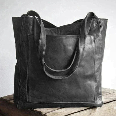 Sac à main en cuir noir élégant sur une table en bois, design moderne et minimaliste, parfait pour la mode urbaine et les tenues décontractées.