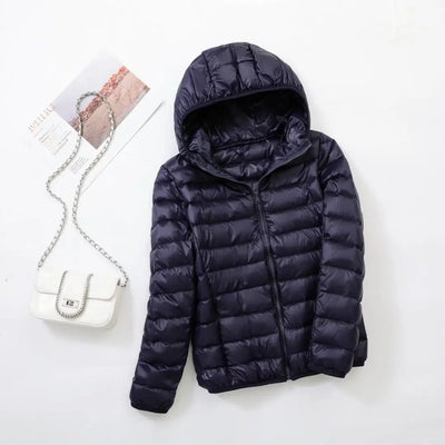 Doudoune noire à capuche posée à plat, accompagnée d'un sac à main blanc avec chaîne argentée. Mode hiver, vêtements chauds, accessoires féminins.