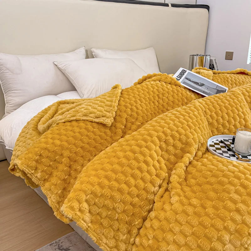 Lit avec couverture en peluche jaune texturée, oreillers blancs, plateau avec tasse et livre, ambiance cosy et moderne, chambre élégante.