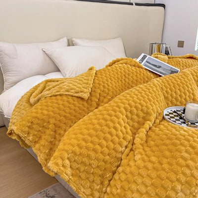 Lit avec couverture en peluche jaune texturée, oreillers blancs, plateau avec tasse et livre, ambiance cosy et moderne, chambre élégante.