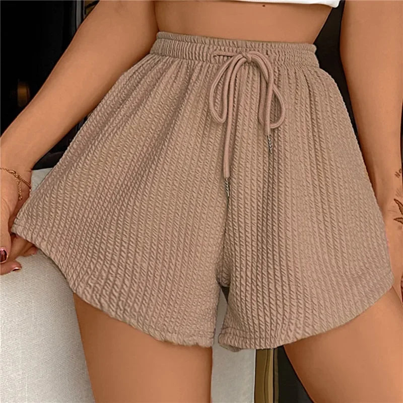 Shorts beiges en tissu texturé avec cordon de serrage, portés par une personne. Mode estivale, confort, style décontracté.