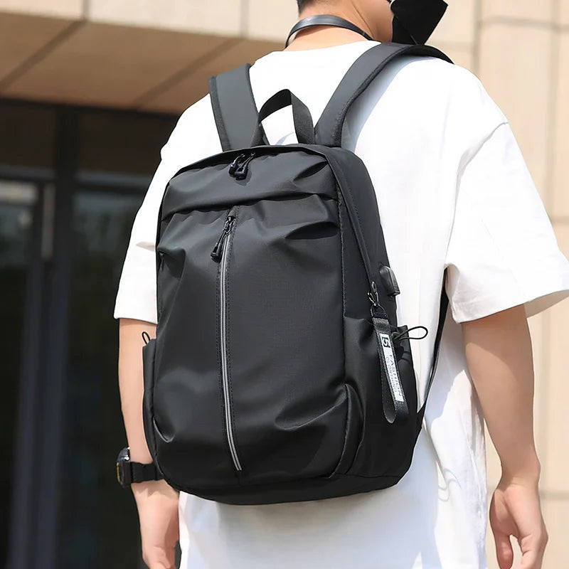 Sac à dos noir moderne porté par une personne en t-shirt blanc, design urbain, idéal pour étudiants et professionnels, tendance et fonctionnel.