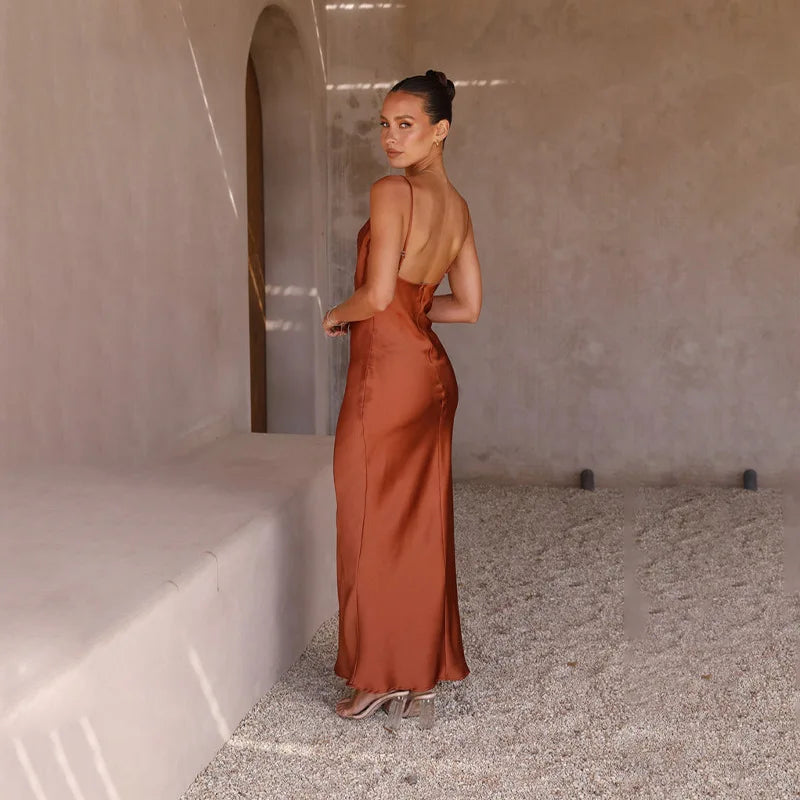 Robe longue dos nu en satin marron, femme élégante, pose dans un intérieur minimaliste, lumière naturelle, style chic et moderne.
