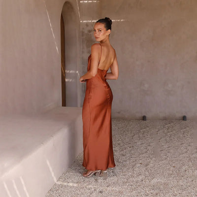 Robe longue dos nu en satin marron, femme élégante, pose dans un intérieur minimaliste, lumière naturelle, style chic et moderne.