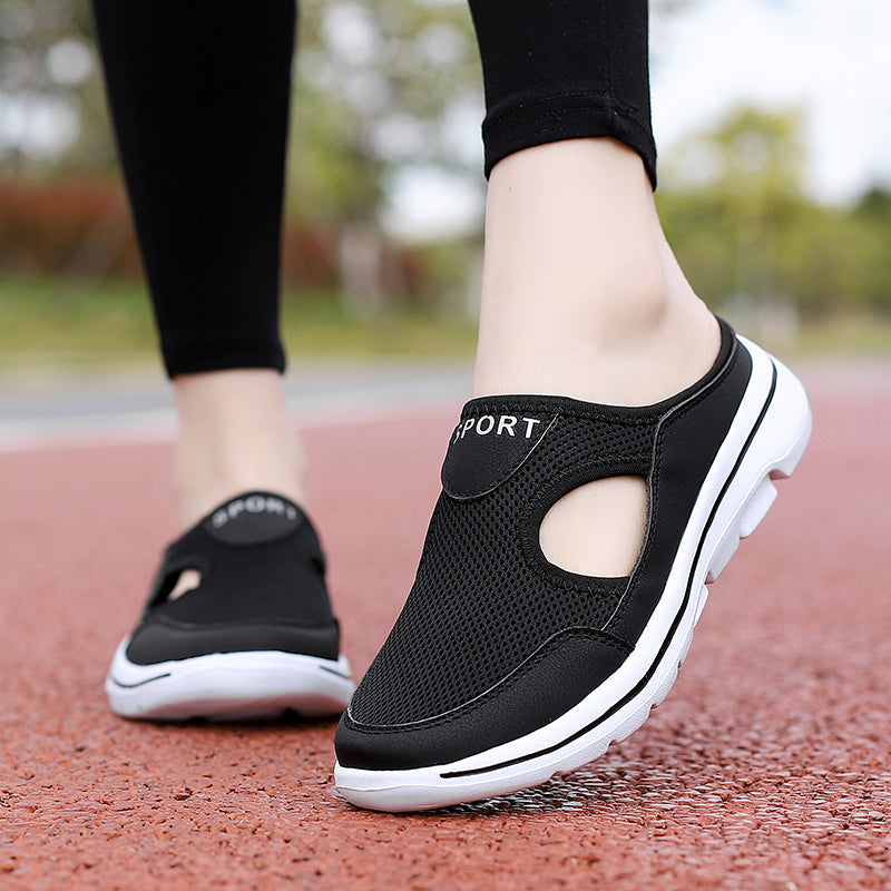 Chaussures de sport noires pour femmes, semelle blanche, design respirant, portées sur une piste rouge. Confort et style pour la marche active.