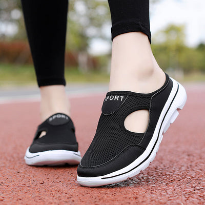 Chaussures de sport noires pour femmes, semelle blanche, design respirant, portées sur une piste rouge. Confort et style pour la marche active.