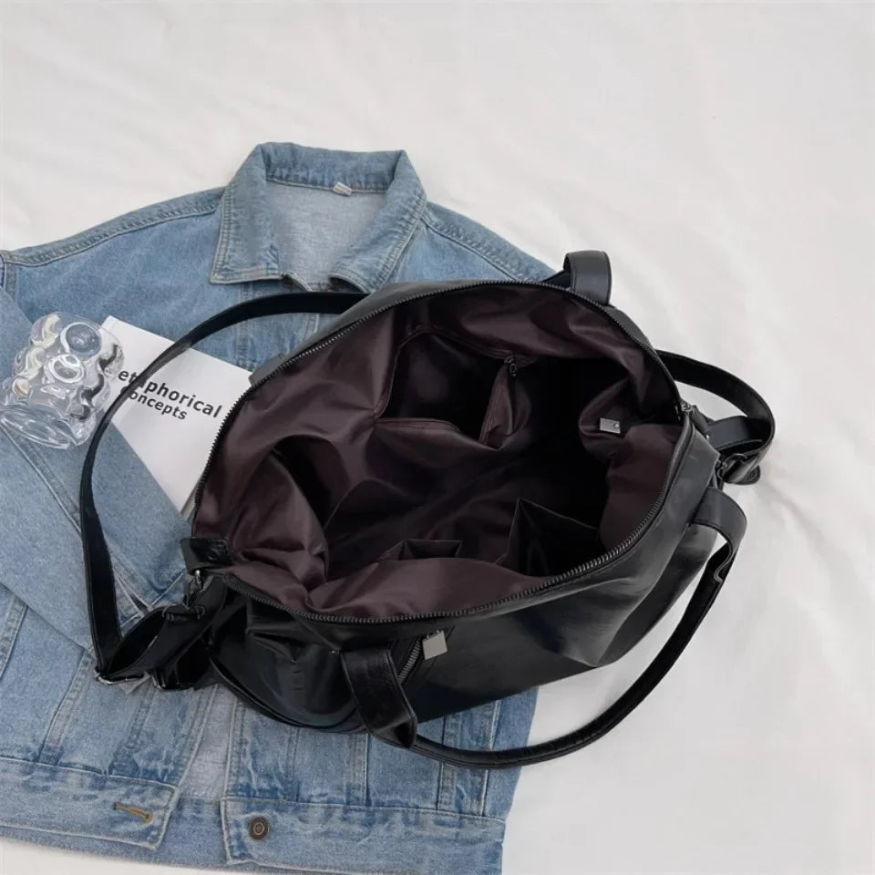 Sac à main noir ouvert sur veste en jean, intérieur spacieux avec poches, design moderne. Accessoire mode tendance pour femme.