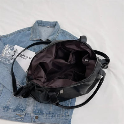 Sac à main noir ouvert sur veste en jean, intérieur spacieux avec poches, design moderne. Accessoire mode tendance pour femme.