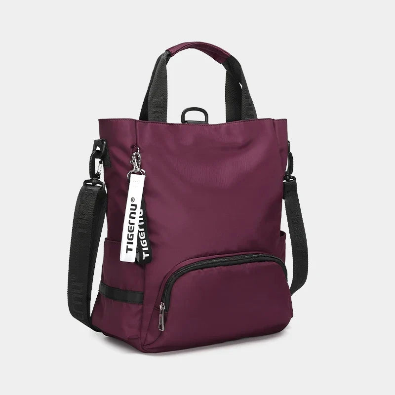 Sac à dos Tigernu violet avec bandoulières noires, poche avant zippée et étiquette de marque. Design moderne et fonctionnel pour usage quotidien.