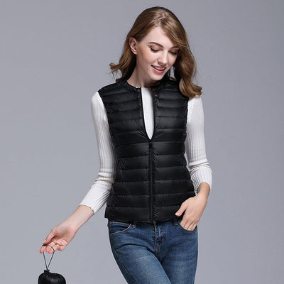 Femme portant un gilet sans manches noir, sur un pull blanc, avec un jean bleu. Mode automne, tenue décontractée, style moderne.