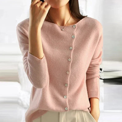 Femme portant un pull rose en cachemire avec boutons, manches longues, col rond, style élégant et décontracté, mode automne-hiver.