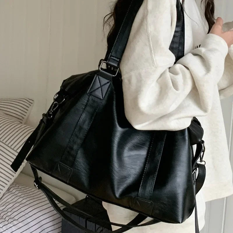 Sac à main noir en cuir porté par une femme en sweat blanc, design élégant et moderne, idéal pour la mode urbaine et les sorties quotidiennes.