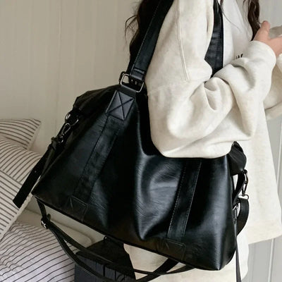 Sac à main noir en cuir porté par une femme en sweat blanc, design élégant et moderne, idéal pour la mode urbaine et les sorties quotidiennes.