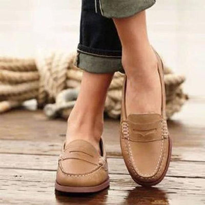 Chaussures mocassins en cuir beige pour femme, portées avec un jean retroussé, sur fond de corde nautique. Mode élégante et décontractée.