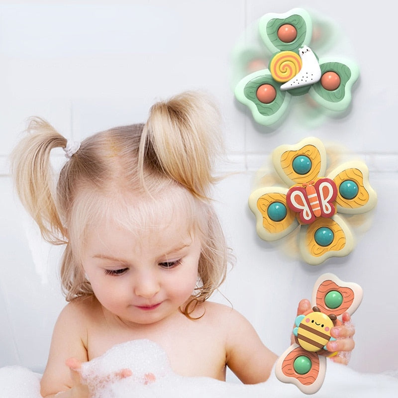 Petite fille jouant dans le bain avec des jouets de bain en forme de papillon, abeille et escargot. Jouets colorés, bain enfant, amusement.