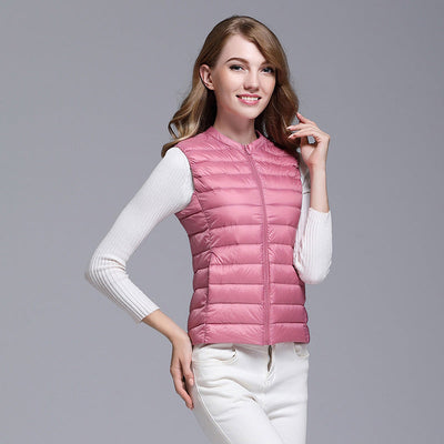 Femme portant un gilet matelassé rose, manches longues blanches, posant sur fond gris. Mode féminine, tenue décontractée, style automne.