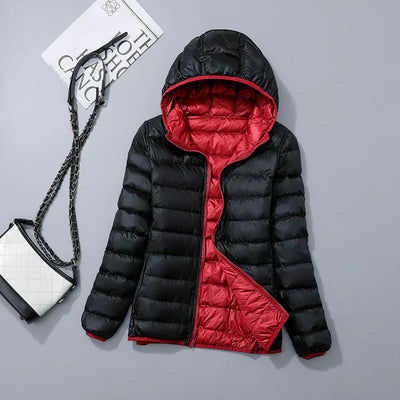 Veste doudoune noire et rouge avec capuche, posée à plat. Sac à main blanc et noir avec chaîne à côté. Mode hiver, vêtements chauds.
