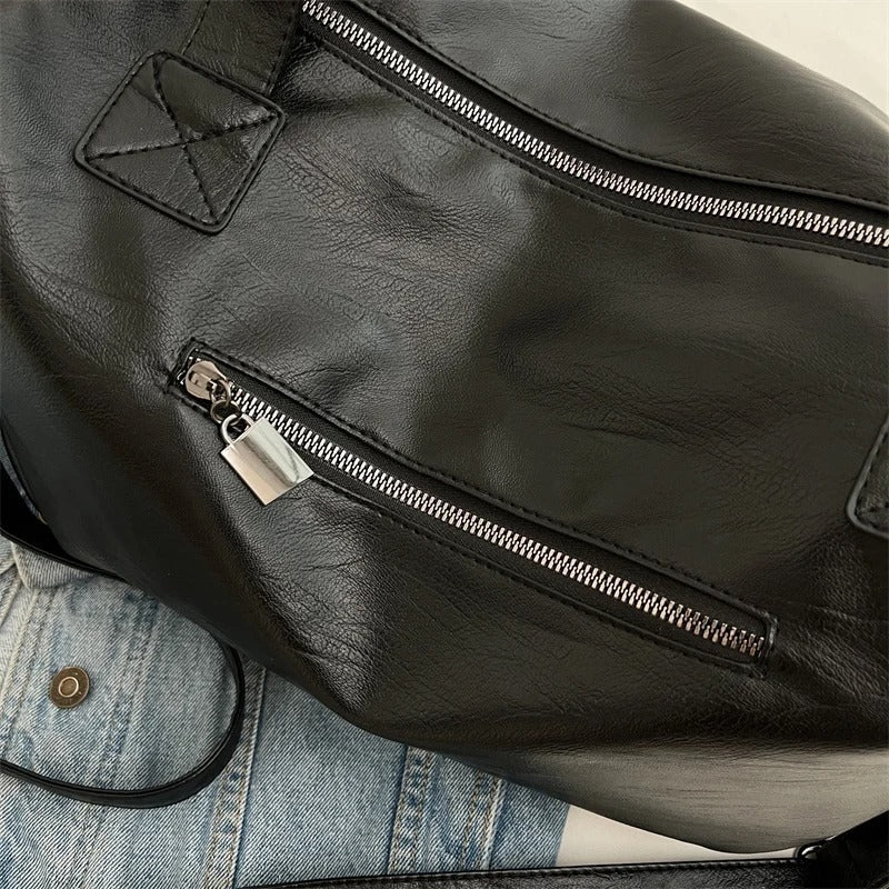 Sac à dos en cuir noir avec fermeture éclair argentée, posé sur une veste en jean. Accessoire mode élégant et tendance pour homme ou femme.