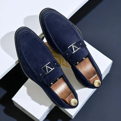 Mocassins en daim bleu marine élégants avec boucle métallique argentée, posés sur fond blanc. Chaussures homme tendance, style chic et moderne.