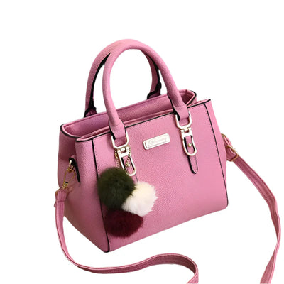 Sac à main rose en cuir avec bandoulière, décoré de pompons colorés. Élégant et tendance, idéal pour un look chic et moderne.