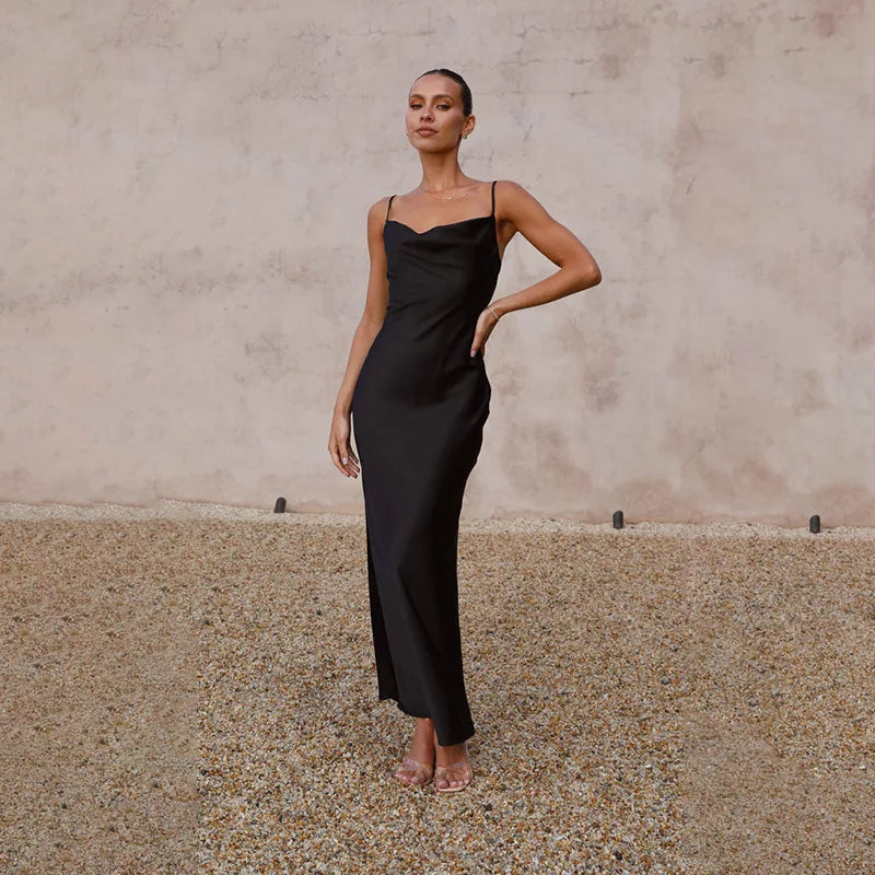 Robe longue noire élégante portée par une femme, posant sur un fond neutre. Mode féminine chic, tenue de soirée sophistiquée.