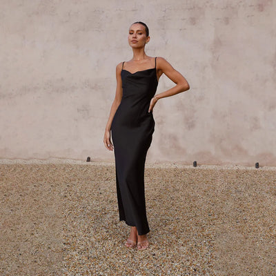 Robe longue noire élégante portée par une femme, posant sur un fond neutre. Mode féminine chic, tenue de soirée sophistiquée.