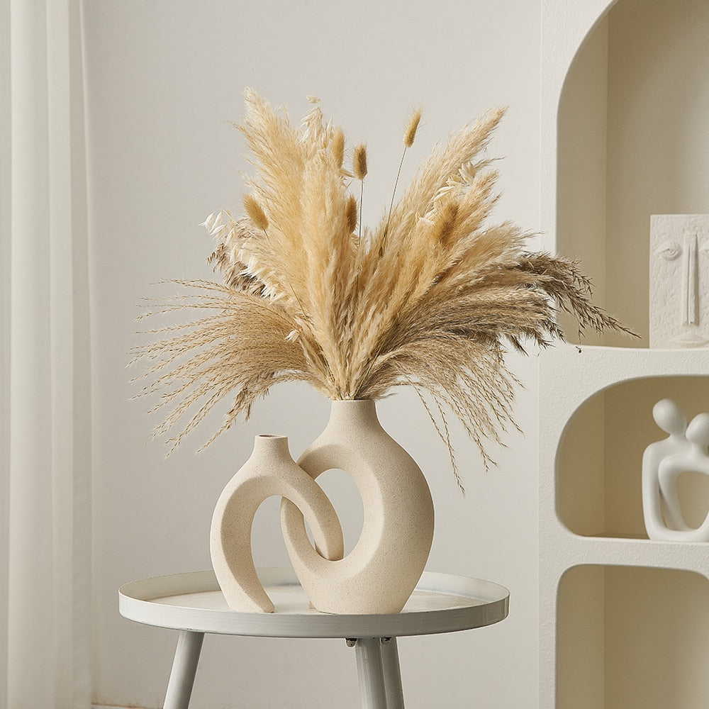 Vase moderne en céramique beige avec pampas séchées, posé sur une table blanche. Décoration intérieure minimaliste et élégante.