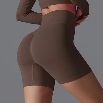 Femme en tenue de sport marron, leggings courts taille haute, mettant en valeur la silhouette. Mode fitness, vêtements athlétiques tendance.