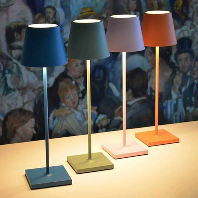 Quatre lampes de table modernes colorées sur une surface beige, avec un fond artistique. Éclairage design, décoration intérieure contemporaine.