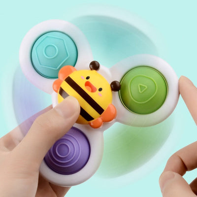Fidget spinner enfant, design abeille, trois branches colorées, jouet anti-stress, fond bleu, mains d'enfant, jeu sensoriel populaire.