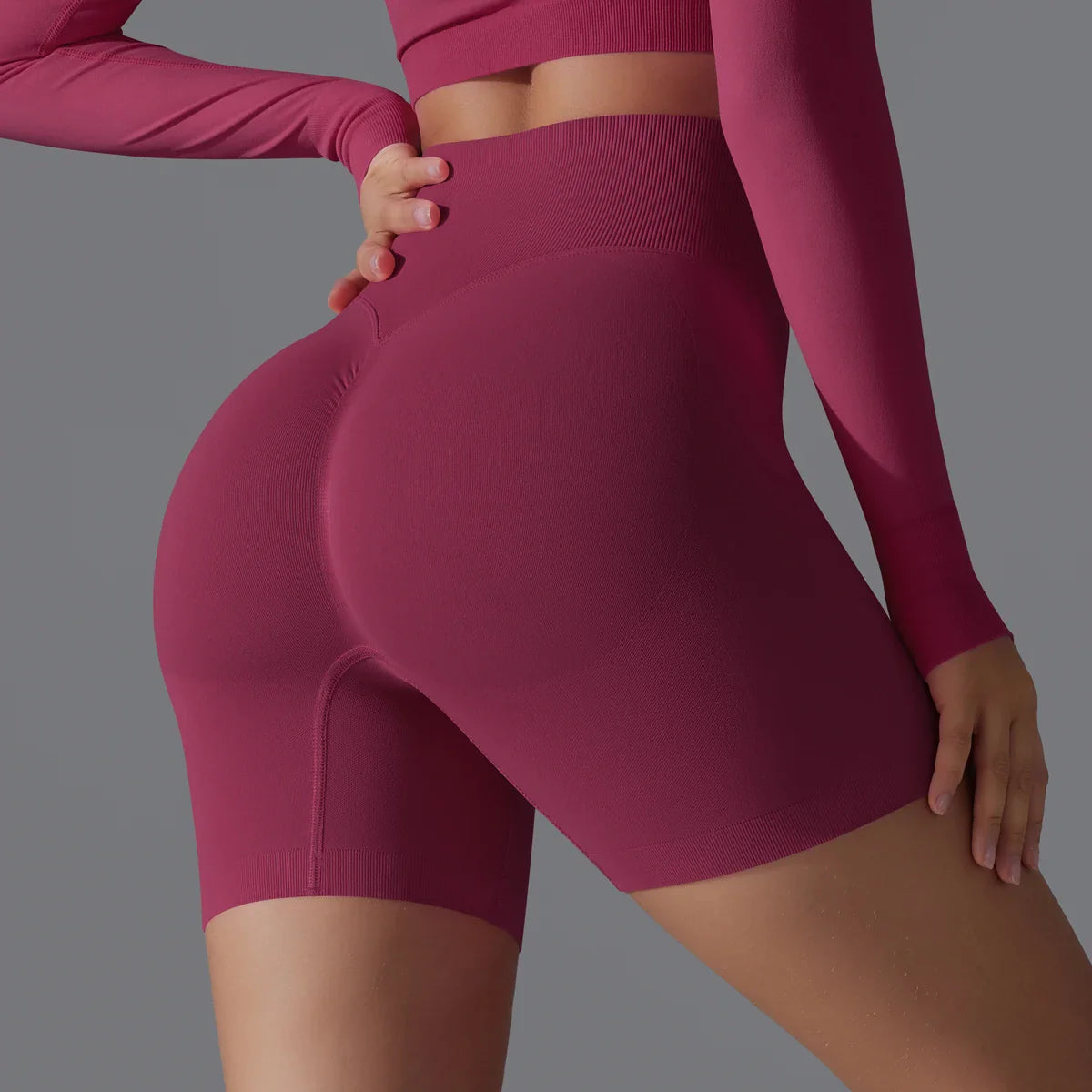 Femme en tenue de sport rose, portant un short moulant taille haute, mettant en valeur la silhouette. Mode fitness, vêtements de sport tendance.