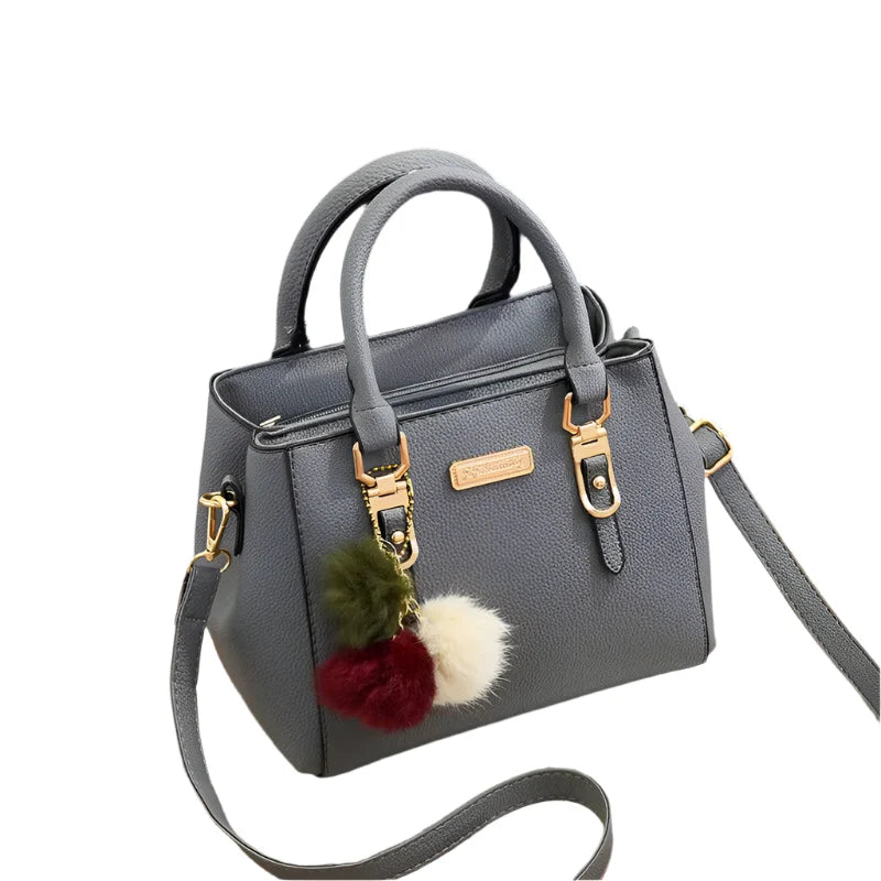 Sac à main gris élégant avec bandoulière, ornements pompons colorés, fermetures dorées. Accessoire mode femme chic et tendance.