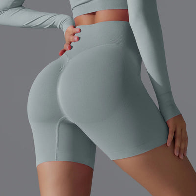 Femme en tenue de sport moulante grise, mettant en valeur des shorts taille haute. Mode fitness, vêtements de sport élégants et confortables.