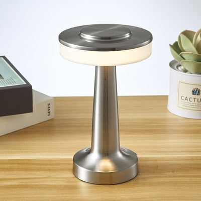 Lampe de table moderne en métal argenté sur bureau en bois, avec livres et plante succulente en arrière-plan. Éclairage LED élégant et contemporain.