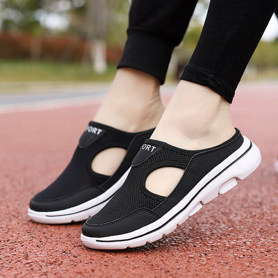 Chaussures de sport noires pour femmes sur piste rouge, design respirant avec semelle blanche, idéales pour la marche et le fitness en extérieur.