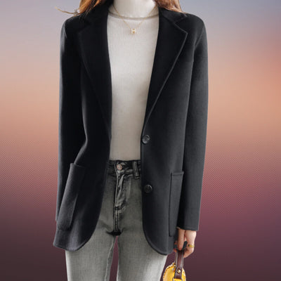 Veste blazer noir femme élégante, manches longues, portée sur un pull blanc, avec jean décontracté. Mode automne-hiver, style chic et moderne.