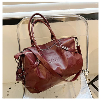 Sac à main en cuir marron sur une chaise transparente, design élégant avec bandoulière, idéal pour mode féminine et accessoires tendance.