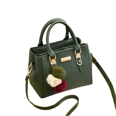 Sac à main vert en cuir avec bandoulière, orné de pompons colorés. Élégant et moderne, idéal pour la mode féminine et les accessoires tendance.