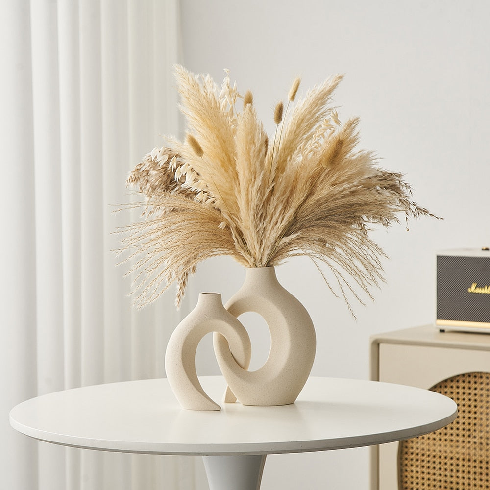 Vase moderne en céramique beige avec bouquet de pampas séchées sur table blanche, intérieur minimaliste, décoration élégante et tendance.