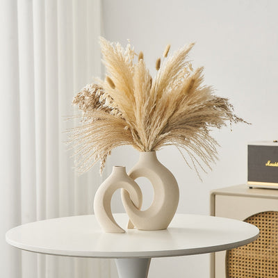 Vase moderne en céramique beige avec bouquet de pampas séchées sur table blanche, intérieur minimaliste, décoration élégante et tendance.