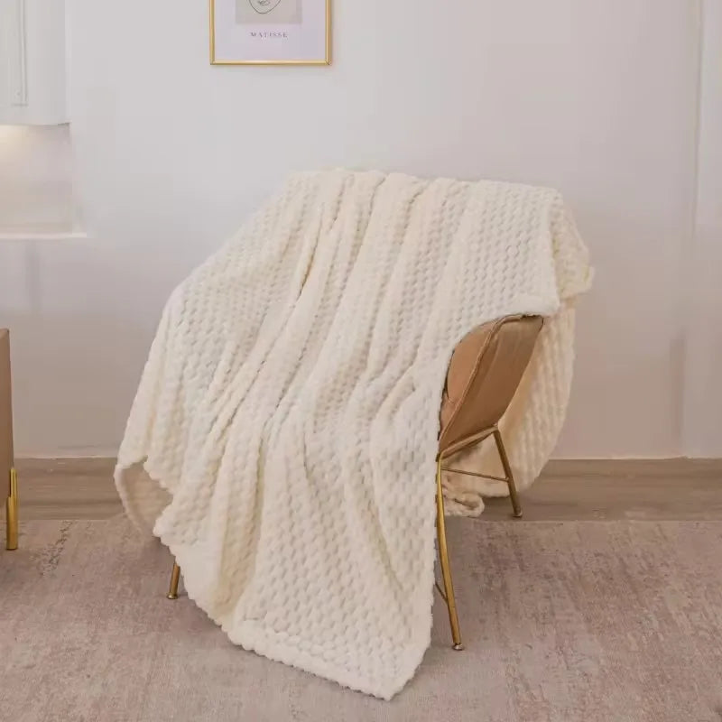 Plaid en laine blanche texturée sur une chaise moderne en métal doré, intérieur minimaliste. Couverture douce, décoration salon élégante.