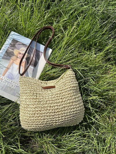 Sac en paille tressée beige sur herbe verte, à côté d'un magazine. Mode estivale, accessoire tendance, style décontracté.