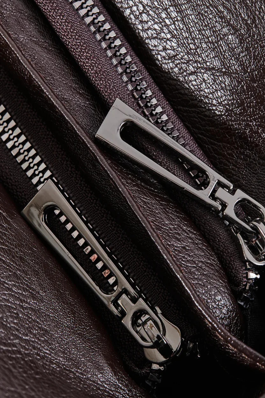Gros plan sur une fermeture éclair métallique sur cuir marron foncé, texture luxueuse, accessoires de mode, détails de sac en cuir élégant.