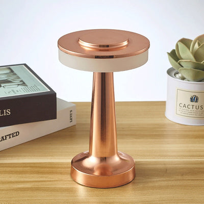 Lampe de table en cuivre moderne sur bureau en bois, à côté de livres et d'une plante en pot. Éclairage design, décoration intérieure élégante.