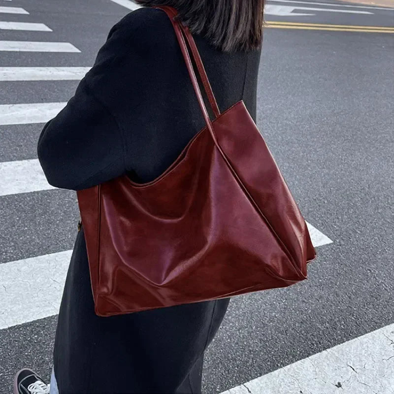 Sac à main en cuir marron porté par une personne en manteau noir, sur un passage piéton. Accessoire mode élégant et tendance pour femme.