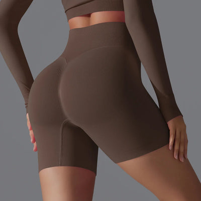Femme en short de sport marron taille haute, mettant en valeur la silhouette. Mode fitness, vêtements de sport, style athlétique moderne.