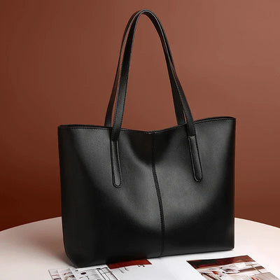 Sac à main en cuir noir élégant sur fond marron, design minimaliste, anses longues, parfait pour mode féminine, accessoire tendance et chic.
