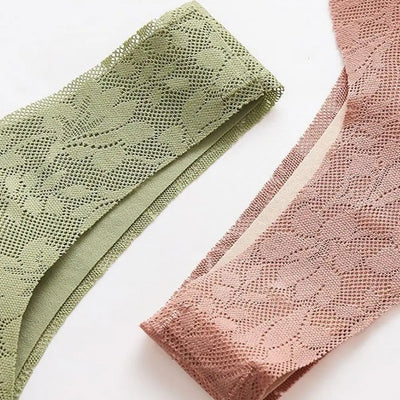 Deux culottes en dentelle, une verte et une rose, posées sur une surface blanche. Lingerie féminine élégante et délicate.