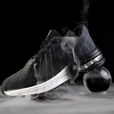 Chaussure de sport noire moderne avec semelle blanche, entourée de fumée, posée sur une sphère transparente. Design élégant et tendance.
